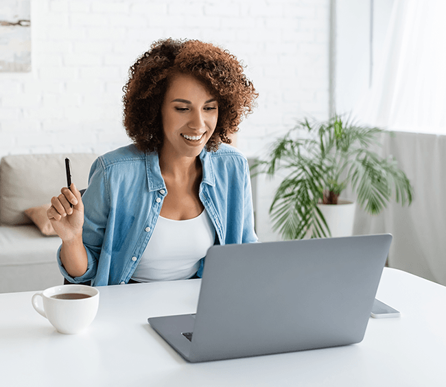 Smiling businesswoman with a cup of coffee looks at her laptop in her office