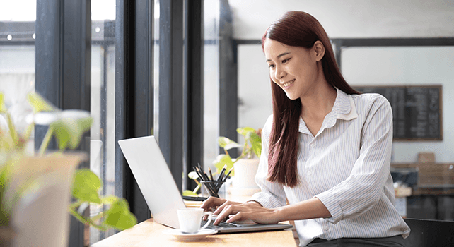 Smiling businesswoman with a cup of coffee looks at her laptop in an office building